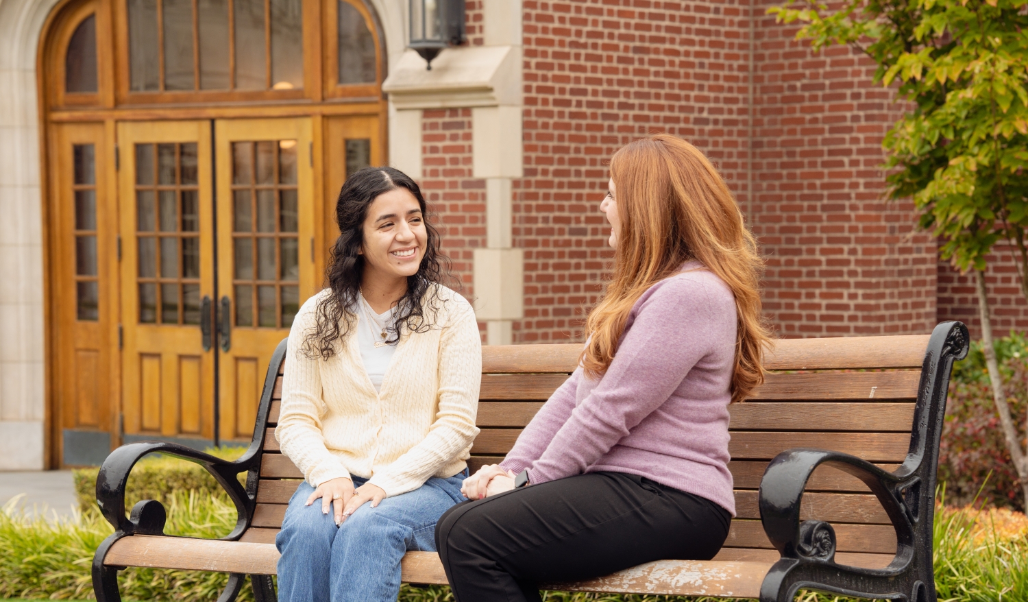 A UP student and her advisor sit on a bench outside Dundon Berchtold Hall.