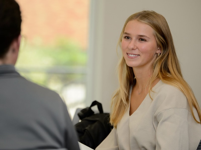 A smiling student meets with a financial aid team member to discuss options