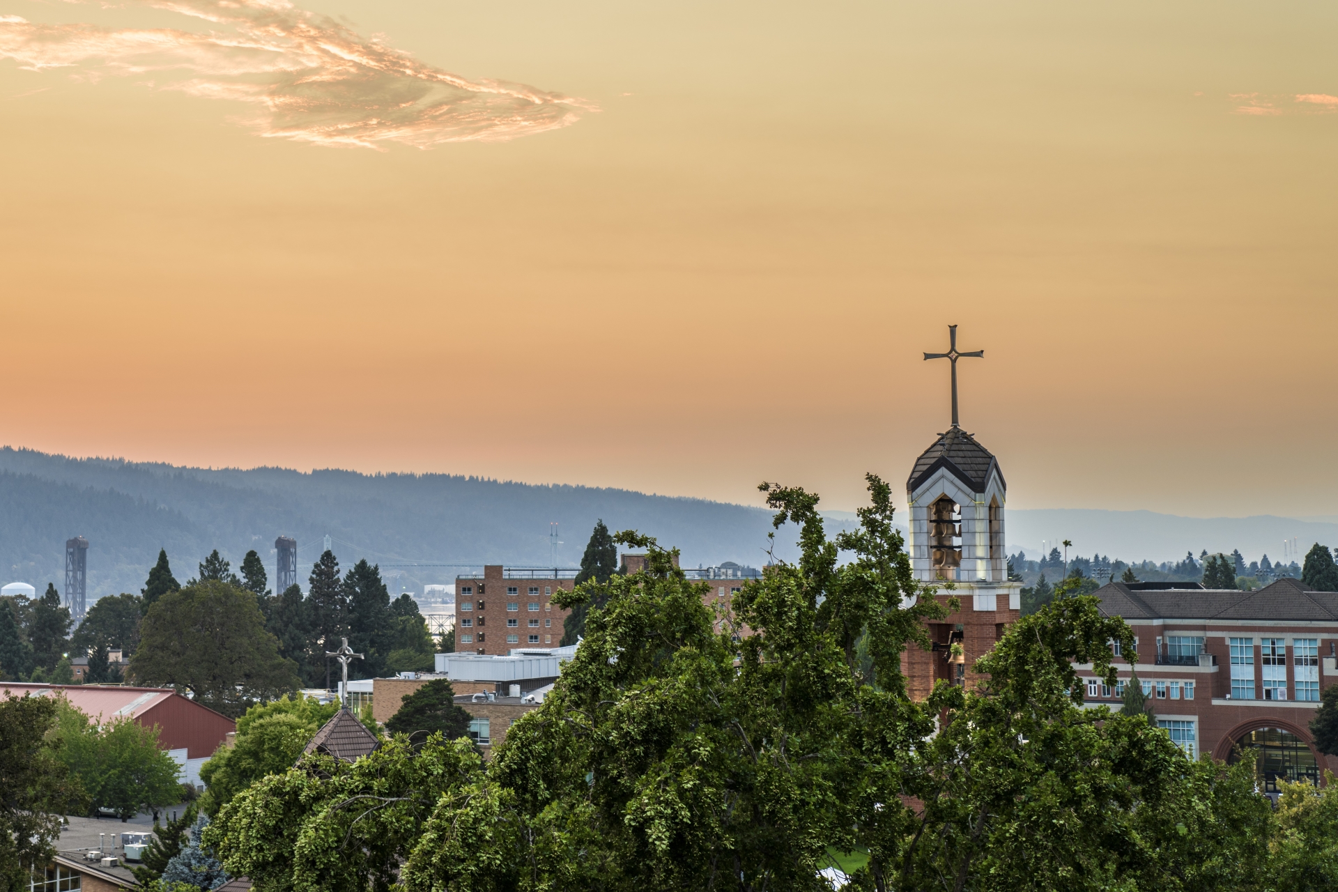 An aerial image of the belltower and the hills of Forest Park at sunset..