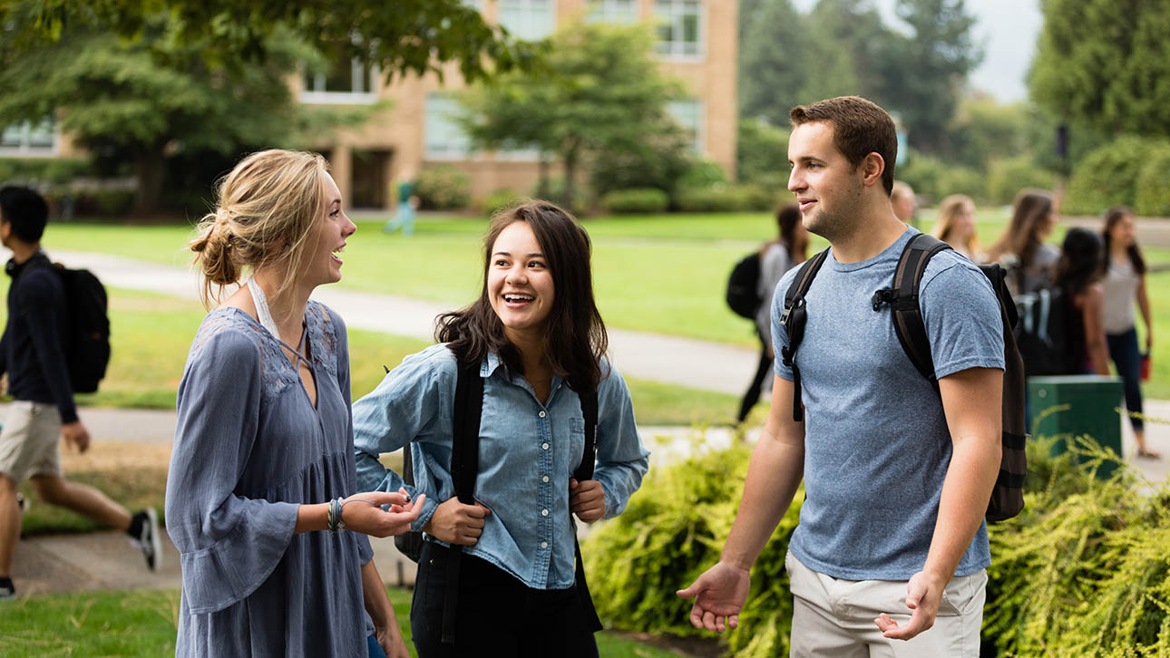 Three students smile while talking on the UP campus
