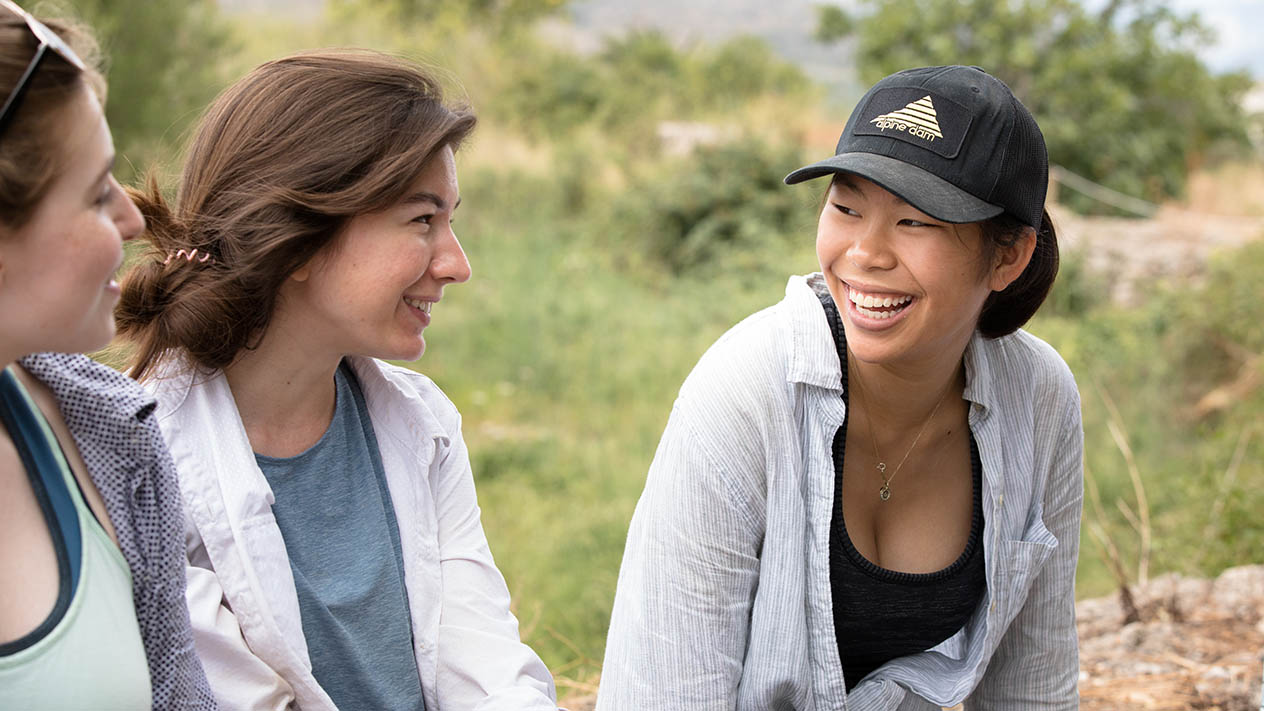 An international student smiles while looking at two other students