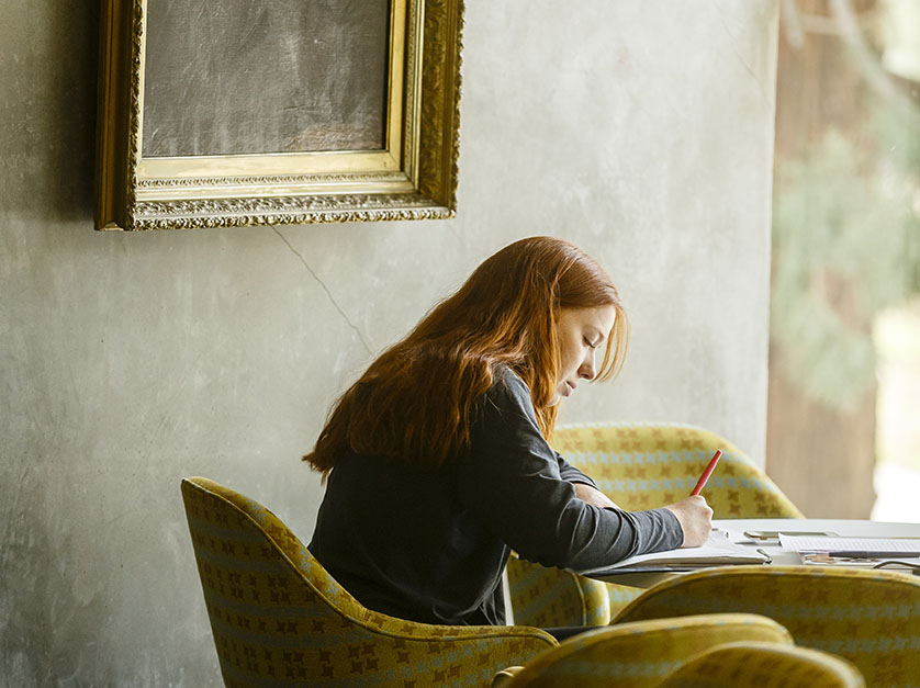 A student works in the Clark Library underneath an ornate painting
