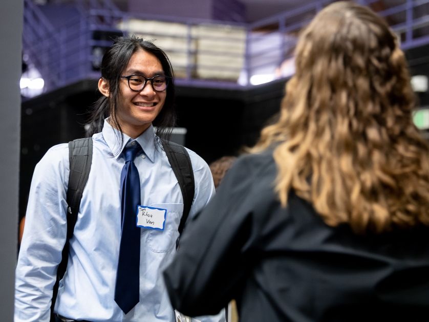 A student intern smiles while speaking with a woman in professional attire