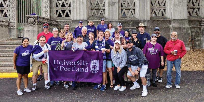 UP alumni holding a University of Portland flag at the UP vs Cal Berkeley Soccer Game.