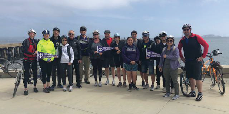 UP alumni posing by the water with their bikes.