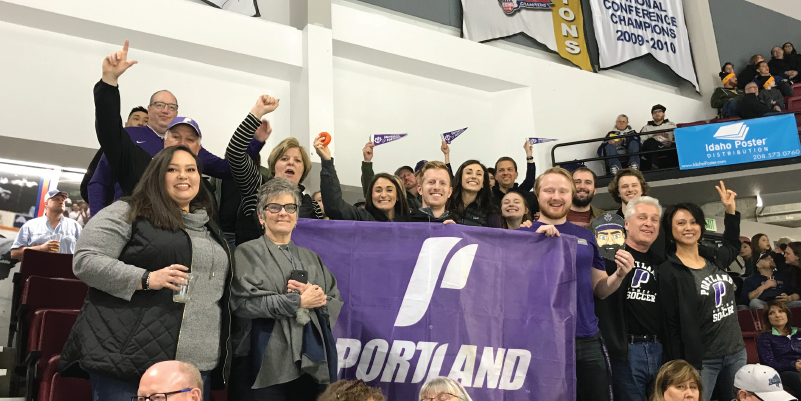 Boise Alumni holding a UP flag at a hockey game