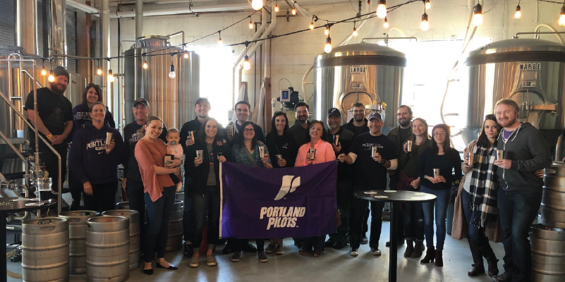 Boise Alumni holding a University of Portland flag in a brewery