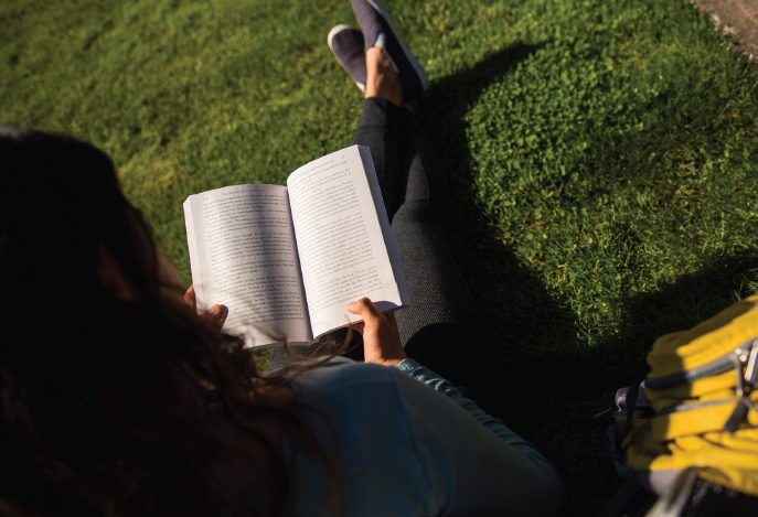 Image of student reading book on campus