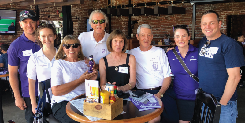 Alumni sitting at a table at a Rockies baseball game