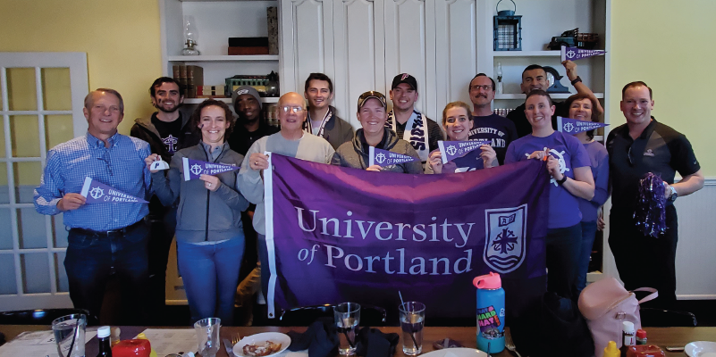 Alumni holding a UP flag at the Rockies pregame