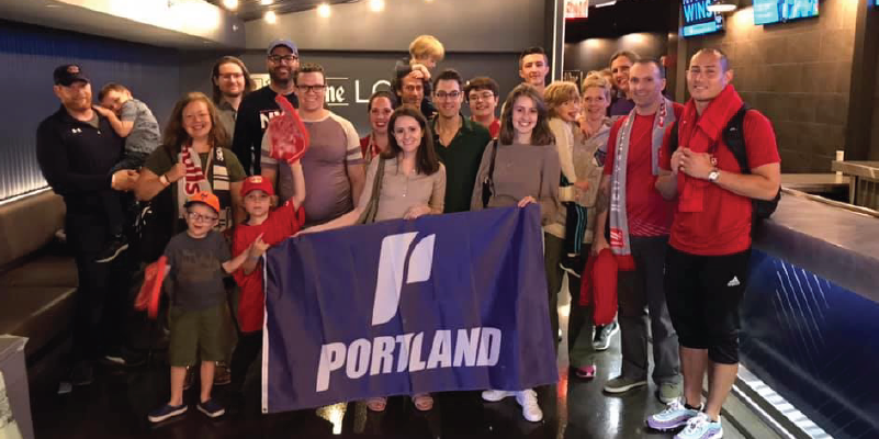 Alumni at a Red Bulls game holding a UP flag.