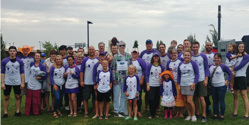 Alumni and their families dressed in white and purple for a Saints game.