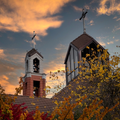 The UP bell tower and chapel steeple against a sunset sky in Fall.