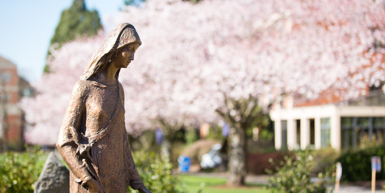 Statue of Mary in front of cherry blossoms