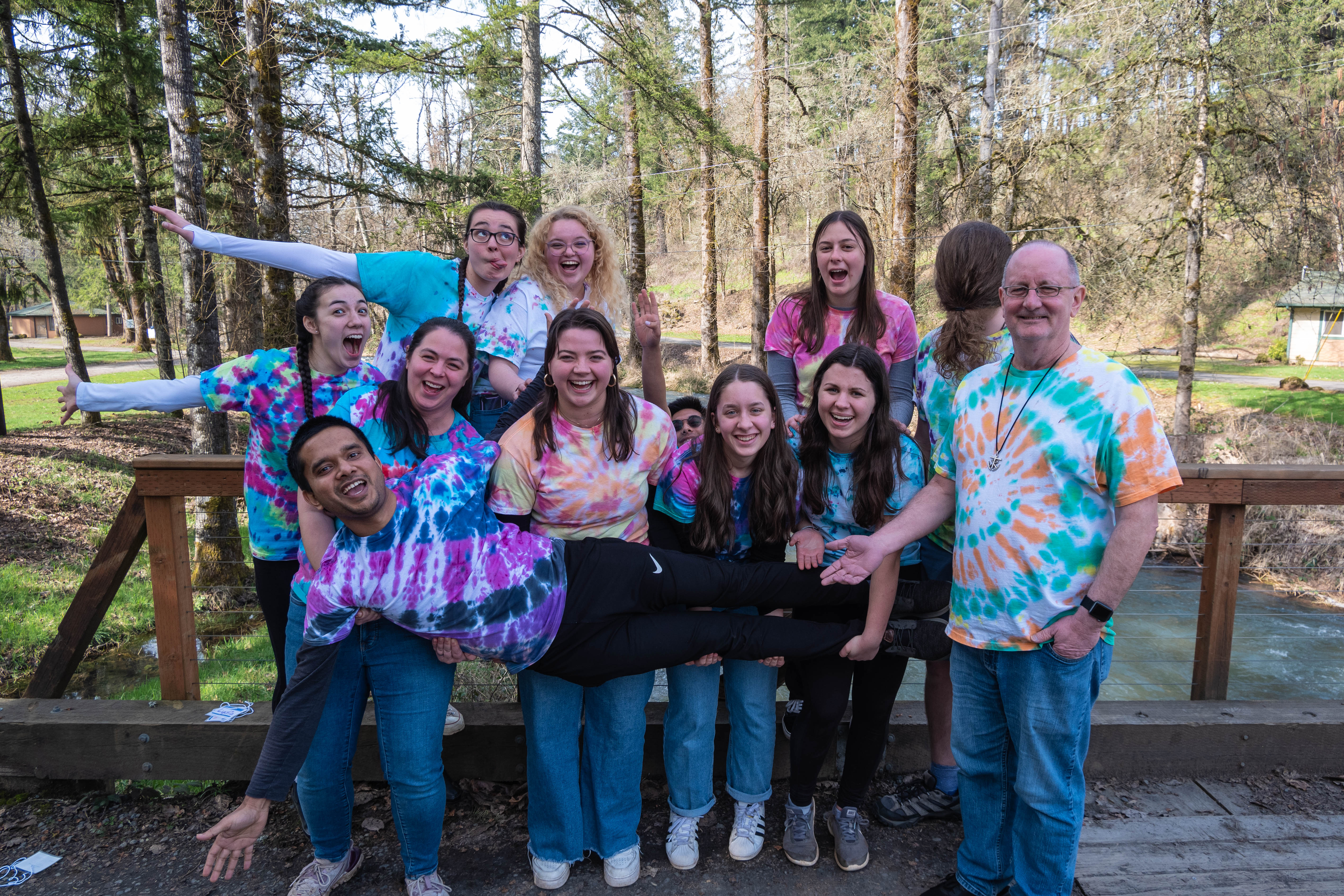 The Spes Unica Retreat Team poses for a photo on a bridge at the retreat site in tie-dyed t-shirts.