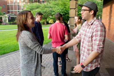 Students shaking hands in front of the Chapel of Christ the Teacher