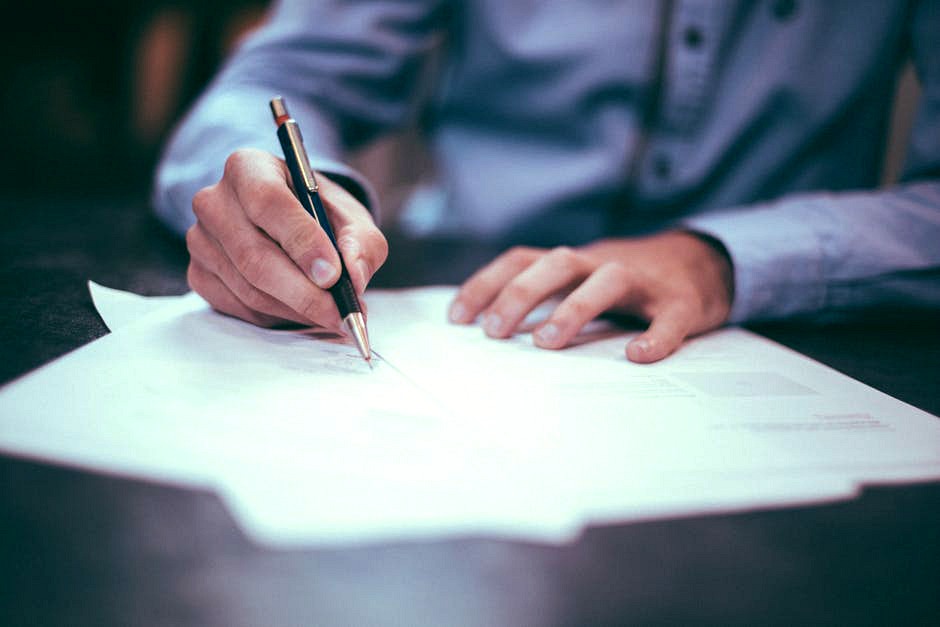 Hands holding a pen writing on documents