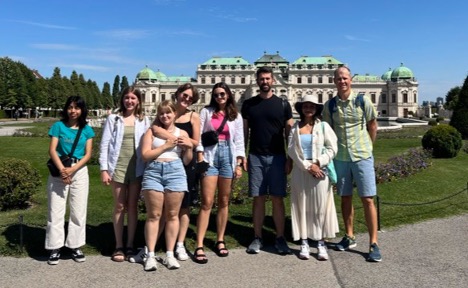 A group of students and faculty pose for a photo in front of the Belvedere Palace