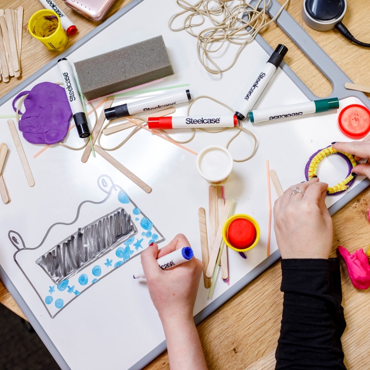 hands working with craft and office supplies on white board flat on table.