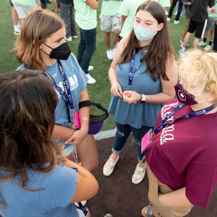 four masked students standing in a circle