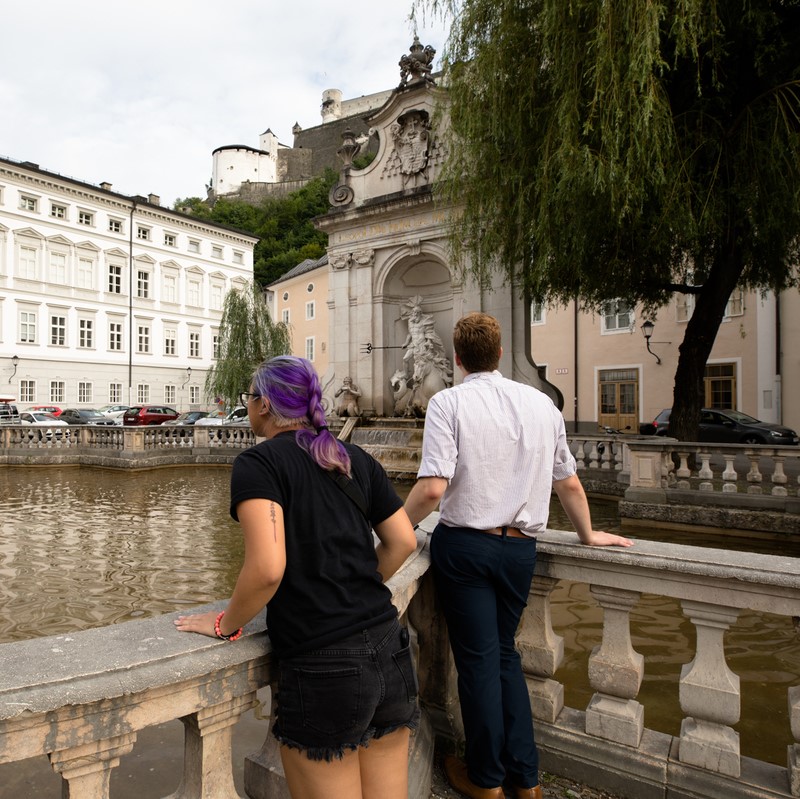 two students overlooking a man-made pond by a willow tree in downtown Salzburg