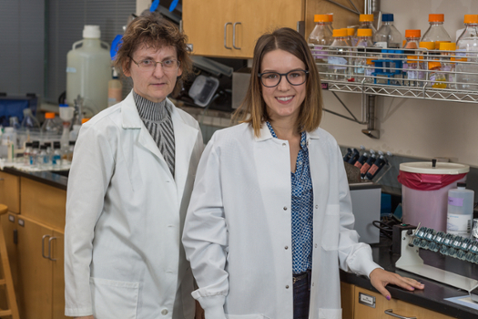 professor Ami Ahern-Rindell and student Alex Quackenbush pose in lab coats in lab