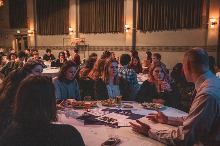 students and staff conversing at table while eating