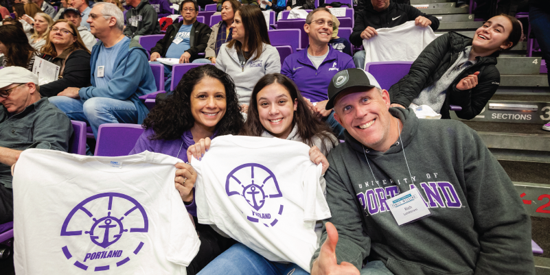 Parents and daughter holding up Pilots t-shirts in basketball stands