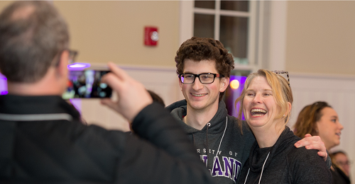 Man taking a photograph of a student and parent