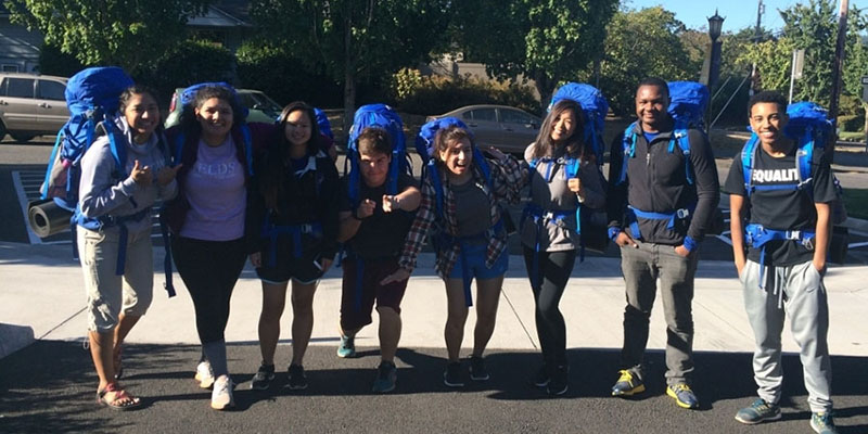 studens with backpacks standing outside, smiling