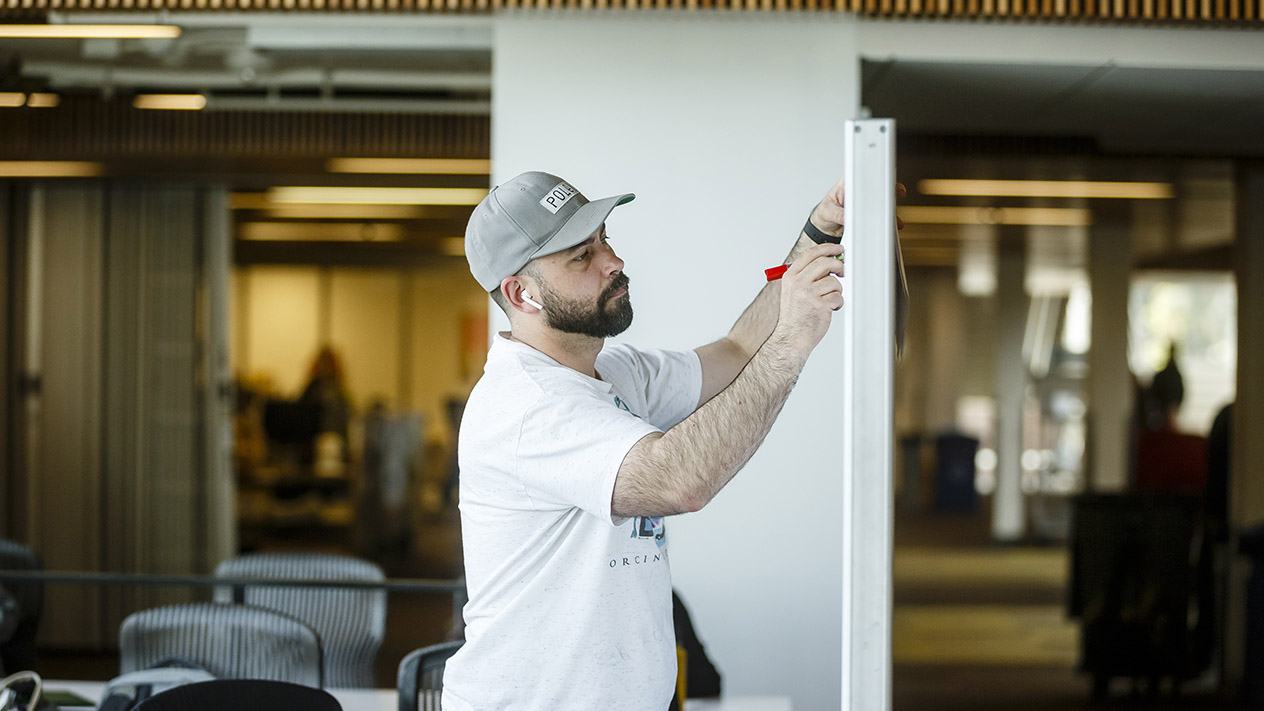 A student wearing headphones and using a marker on a dry-erase board