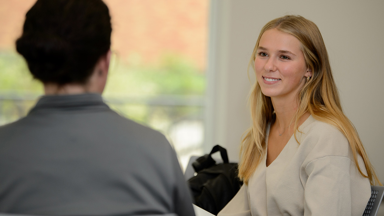 A smiling student meets with a financial aid team member to discuss options