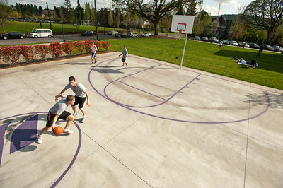 four students playing basketball outside