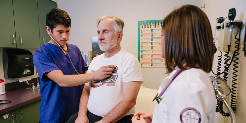 nursing student examines patient while professor observes.