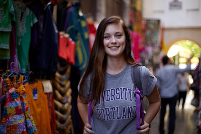 student in a UP t-shirt standing in an international market