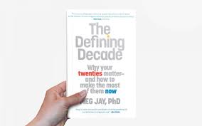 A hand holding up the book "The Defining Decade".
