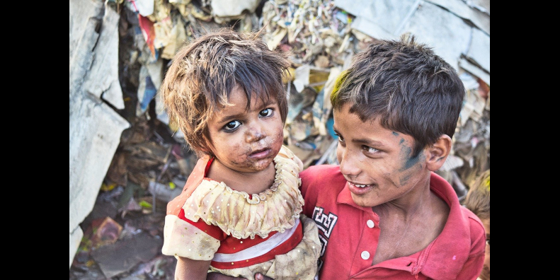 boy and girl with dirty faces standing in front of a pile of garbage