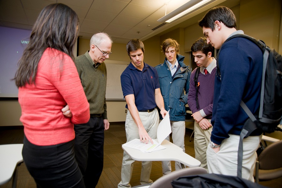 students gathered around a desk looking at a paper