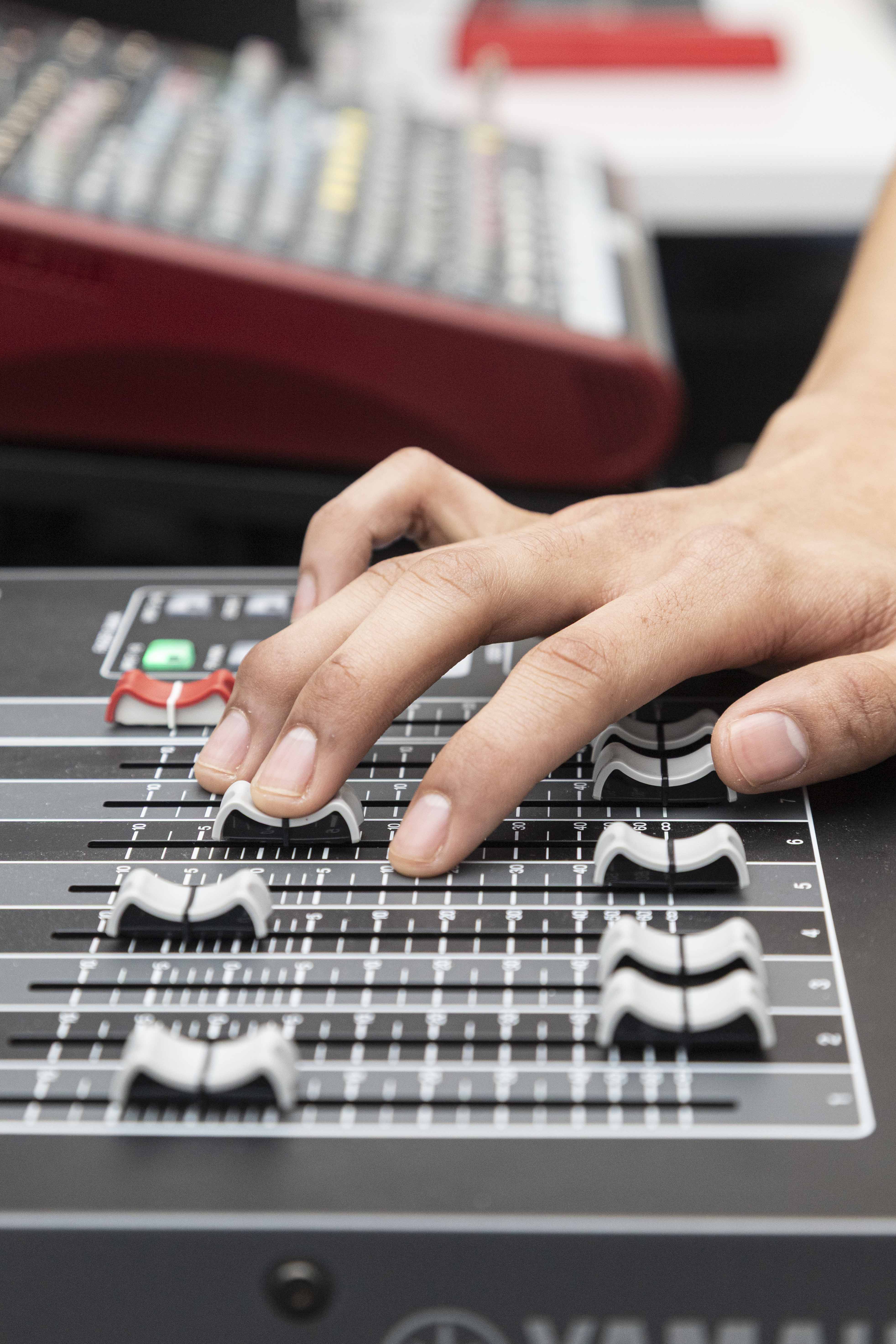 Hand sliding audio mixer fader.