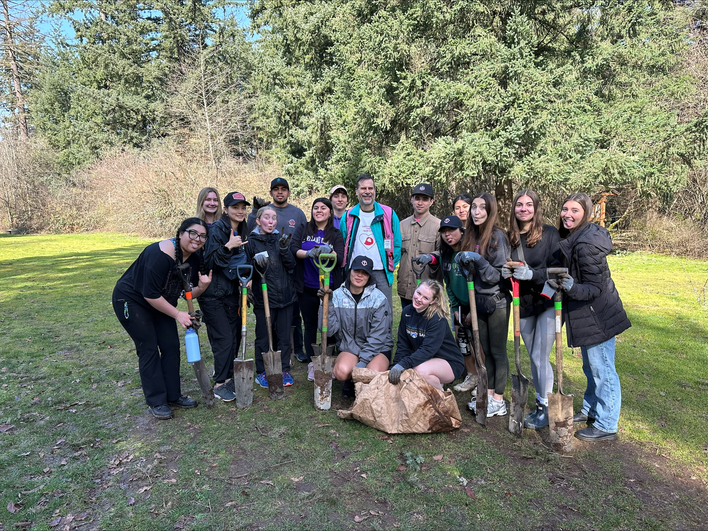 a service and justice coordinator event with field halls. students standing outside with shovels after planting trees.