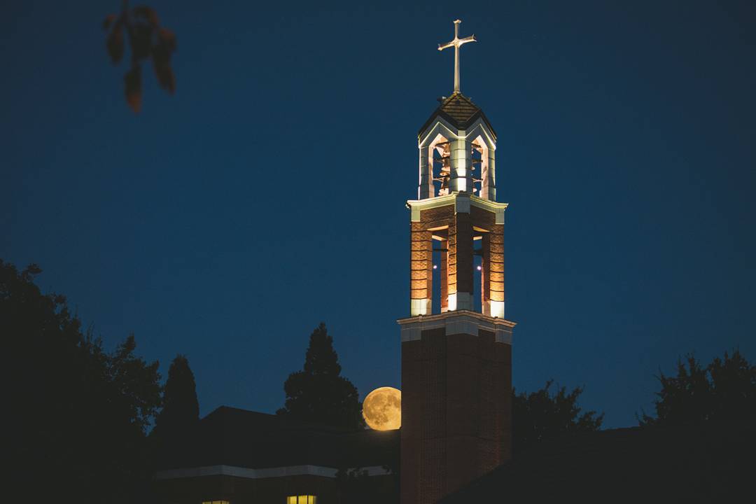 photograph of large moon and chapel 