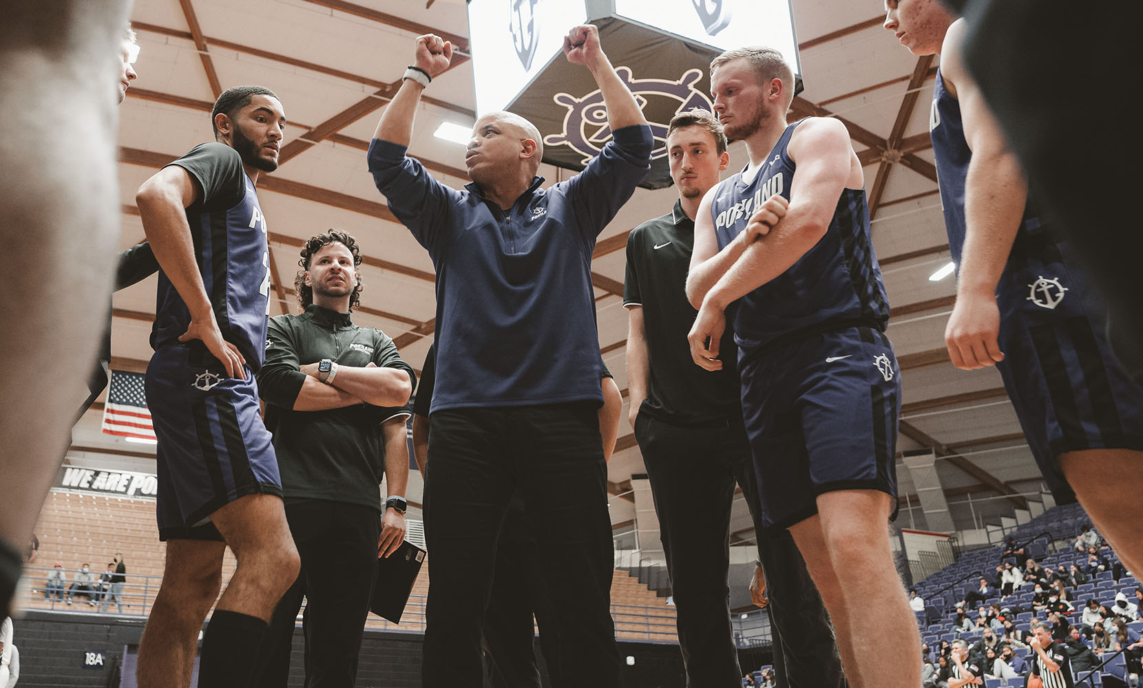 Men's basketball team on the court with coach Shantay Legans in the center