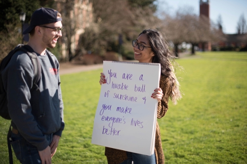 girl holding sign that reads, "You are a lovable ball of sunshine and you make everyone lives better"