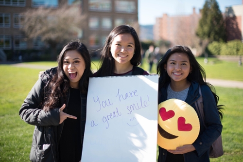 three girls holding sign that reads, "You have a great smile!"