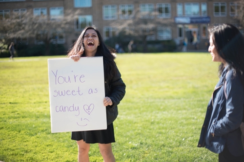 girl laughing and holding a sign that reads, "You are as sweet as candy"