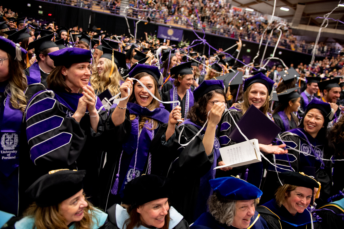 A crowd of students in caps and gowns smile excitedly at the UP commencement ceremony in the Chiles Center.