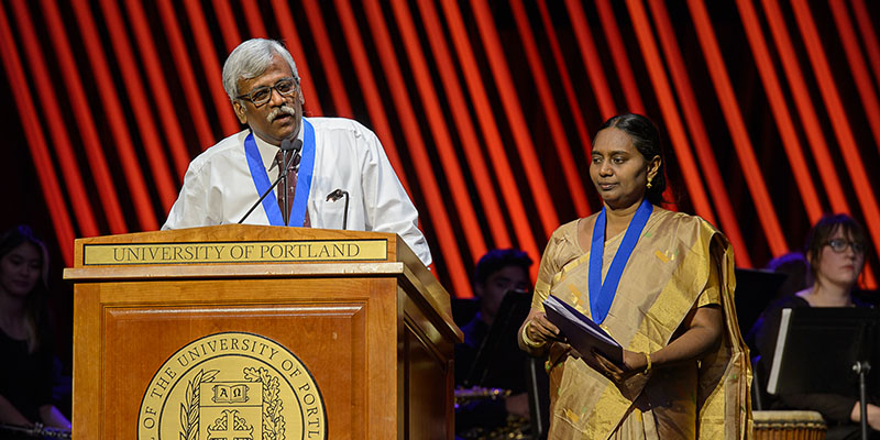 Daniel and Avitha Victor speaking on stage at podium