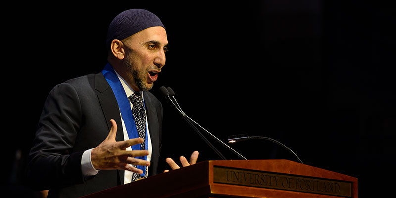 Dr. Rami speaking on stage at podium