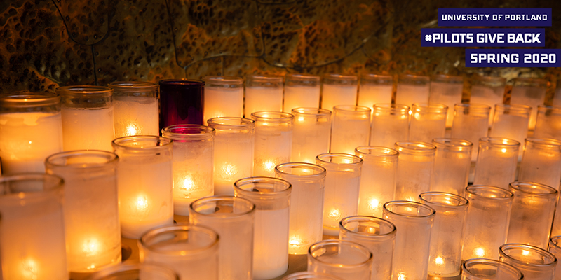 candles lit in grotto with logo that reads University of Portland Pilots Give Back Spring 2020