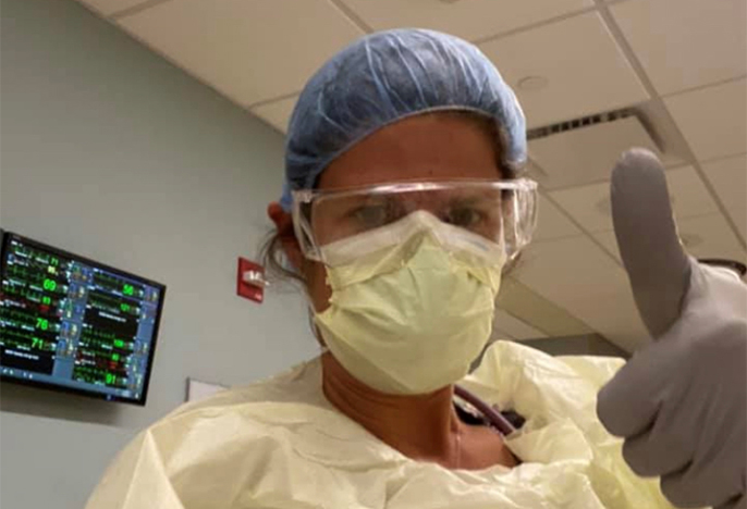 nurse giving thumbs up in protective scrubs